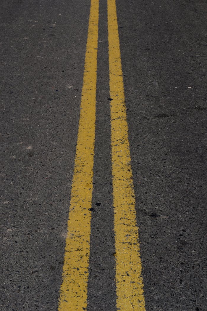 Detailed view of double yellow lines on asphalt road surface.
