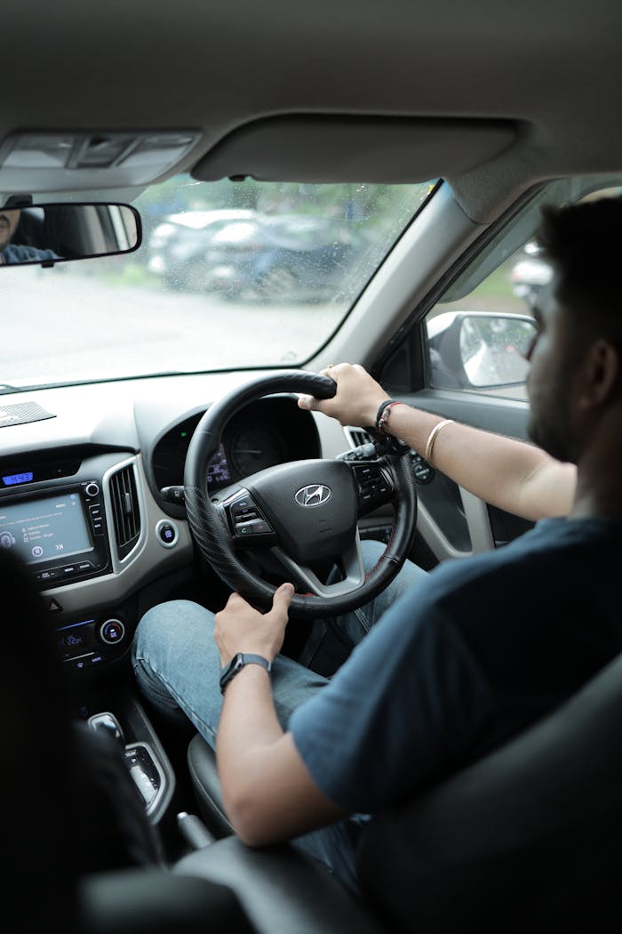 Young man driving a car focusing on the road, showcasing modern vehicle interior.